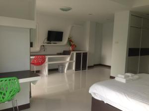 Habitación de hotel con cama, escritorio y TV. en Praiyanan Place Hotel, en Maha Sarakham