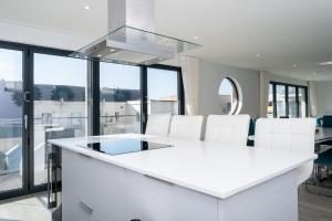 una cocina con una isla blanca y sillas blancas en 6 Challacombe - Luxury Apartment at Byron Woolacombe, only 4 minute walk to Woolacombe Beach!, en Woolacombe