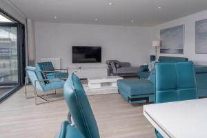 sala de estar con sillas azules y TV en 6 Challacombe - Luxury Apartment at Byron Woolacombe, only 4 minute walk to Woolacombe Beach!, en Woolacombe