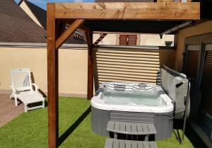 a hot tub on a patio with a chair at Gîte avec SPA au cœur du vignoble d'Alsace in Sigolsheim