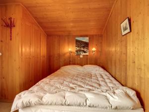ein großes Bett in einem Zimmer mit Holzwänden in der Unterkunft Gavroche Combles in Verbier