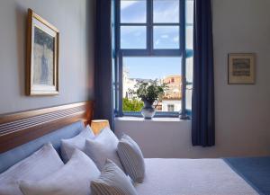 a white bed sitting in front of a window at Orloff Boutique Hotel in Hydra