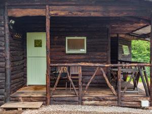 a wooden cabin with a green door and a window at The Log Cabin in Honiton
