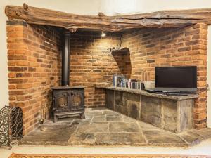 a brick wall with a television and a stove at The Log Cabin in Honiton