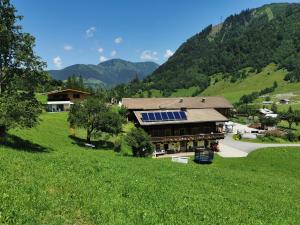 una casa con paneles solares al lado de una colina verde en Entfeldhof - Familie Schernthaner, en Fusch an der Glocknerstrasse