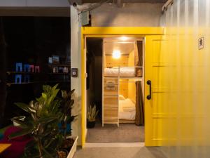 Khao San Social Capsule Hostel في بانكوك: باب أصفر يؤدي إلى غرفة نوم مع سرير بطابقين