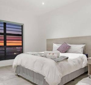 1 dormitorio con 1 cama blanca grande y ventana en Pearl Haven, beach house with magnificent views!, en Yzerfontein