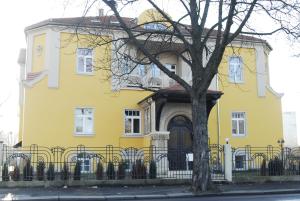 een geel huis met een hek ervoor bij Villa De Baron in Dresden