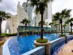 a large swimming pool with palm trees in a city at Vortex suites klcc by Surat in Kuala Lumpur