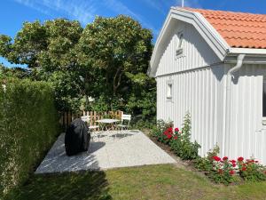 a small white building with a table and chairs next to it at Attefallshus på Ängö i Kalmar in Kalmar
