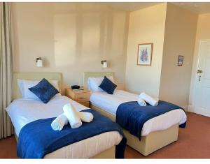 um quarto de hotel com duas camas com lençóis azuis e brancos em Bonair Hotel em Paignton