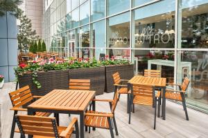 deux tables et chaises en bois devant un magasin dans l'établissement MyContinental Bucuresti Gara de Nord, à Bucarest