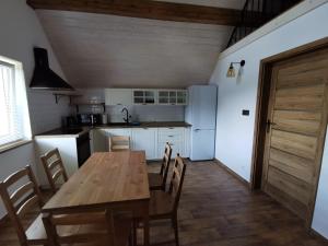 a kitchen with a wooden table and chairs and a refrigerator at Apartament Jaśmin in Polańczyk