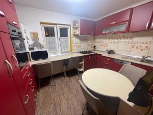 a kitchen with red cabinets and a table and chairs at Apartament Retreat in Drăgăşani