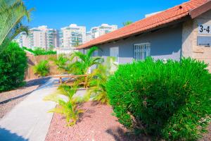 a house with palm trees and a sidewalk at Agamim Hotel Ashkelon in Ashqelon