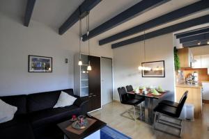 ein Wohnzimmer mit einem schwarzen Sofa und einem Tisch in der Unterkunft Huus vör d Diek Wohnung 1 in Neuharlingersiel