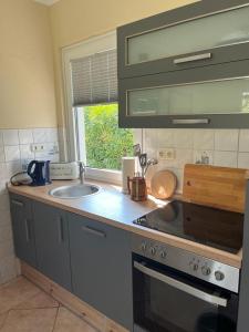 a kitchen with a sink and a stove and a window at Ferienbungalow Zum Anleger 3 in Hohenkirchen
