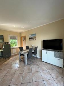 a dining room with a table and a flat screen tv at Ferienbungalow Zum Anleger 3 in Hohenkirchen