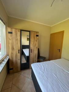 1 dormitorio con cama, espejo y ventana en Ferienbungalow Zum Anleger 3, en Hohenkirchen