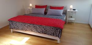 um quarto com uma cama com um cobertor vermelho e almofadas em Apartment Strawberry em Bermatingen