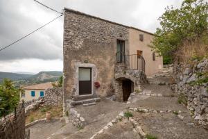 un antico edificio in pietra con una porta su una collina di Lou Baoumoun a Coursegoules