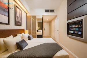 a hotel room with a bed and a flat screen tv at Centrestage Petaling Jaya by Perfect Host in Petaling Jaya