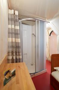 a room with a shower and a wooden table at Péniche Daphné's in Auvers-sur-Oise