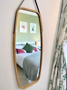a mirror on a wall with a bed in a room at Beautiful Garden Room with Private Entrance in Kingsbridge