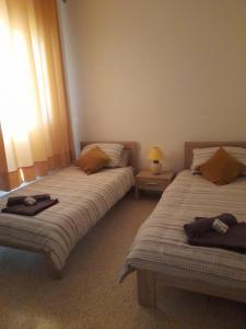 a bedroom with two beds and a lamp and a window at Gozo Marsalforn in Marsalforn