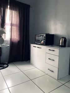 a white dresser with a microwave on top of it at The Eden Lodge Verulam in Verulam