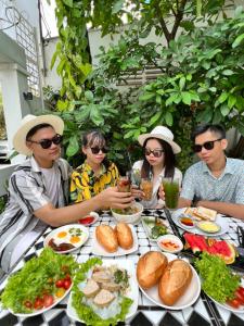 un gruppo di persone seduti a un tavolo con cibo di MIDMOST Villa Hotel a Can Tho