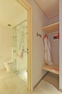 baño con ducha, aseo y puerta de cristal en HARRIS Hotel & Conventions Solo en Solo