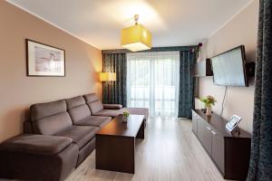 a living room with a couch and a flat screen tv at VacationClub – Aquarius Apartament 99 in Kołobrzeg