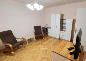 Habitación con 2 sillas, escritorio y TV. en Thermal Hotel en Komárom
