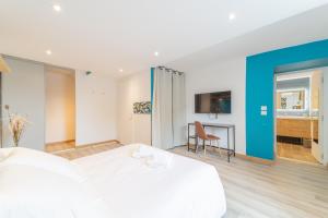 una camera da letto con un grande letto bianco e una scrivania di Côté Cour, 3 chambres, terrasses, jardin privé avec terrain de pétanque, cave voutée a Corgoloin Altre 7 foto