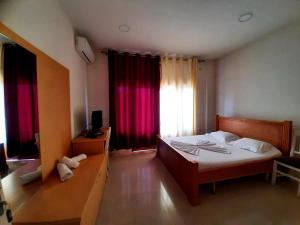 1 dormitorio con 1 cama y una ventana con cortinas rojas en Hotel Vila Giorgio, en Shkodër