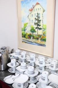 a pile of white dishes on a table with a painting at Hotel Sofia in Bad Wildungen