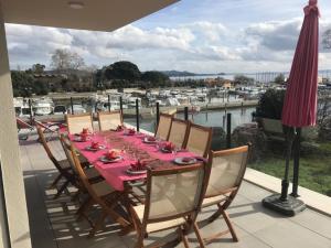 a table with a pink table cloth on a balcony with a marina at SUPERBE VILLA VUE MER JUSQU'A 14 COUCHAGES La LONDE LES MAURES Entre HYERES et Le LAVANDOU 4 Etoiles PISCINE CHAUFFEE in La Londe-les-Maures