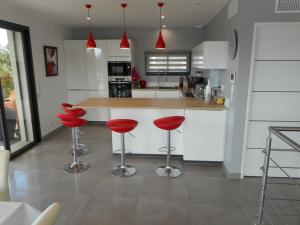 拉隆代勒莫勒的住宿－SUPERBE VILLA VUE MER 4 Etoiles 10 COUCHAGES PISCINE CHAUFFE，厨房在厨房柜台上配有红色凳子
