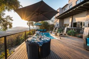 uma mesa com um guarda-sol num deque ao lado de uma piscina em Humdani Game Lodge em Vaaldam