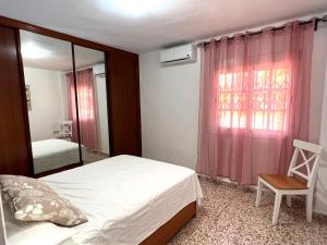 a bedroom with a bed and a window and a chair at Apartamento Isidoro in Fuengirola