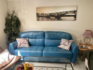 un sofá azul en una sala de estar con una pintura en Puerta de San Juan, en Sevilla