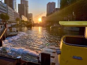 un barco en un río en una ciudad al atardecer en Houseboat holiday apartments Rotterdam en Róterdam