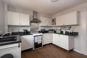 una cocina con armarios blancos y encimeras negras en Pine Park en Ushaw Moor