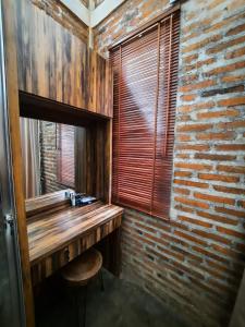 Habitación con escritorio de madera en una pared de ladrillo. en RUMAH @ Sawah Ijen en Licin