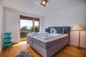 Cama grande en habitación con ventana grande en Künstlervilla mit grandiosem Panoramablick, en Fischbachau