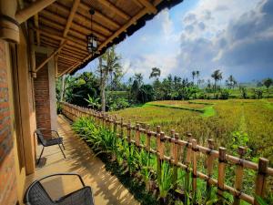 un porche con mesa, sillas y un campo de arroz en RUMAH @ Sawah Ijen en Licin