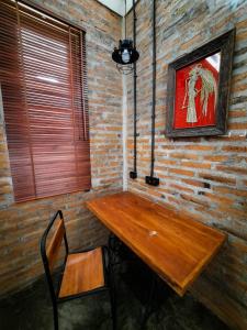 RUMAH @ Sawah Ijen في Licin: طاولة خشبية وكرسي في غرفة بجدار من الطوب