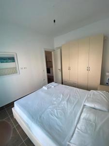 a large white bed in a room with cabinets at Sea view apartament in Sarandë