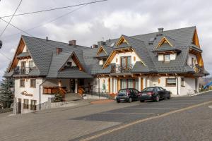 uma casa grande com carros estacionados em frente em Willa Tatrzańska sauna balia w cenie em Murzasichle